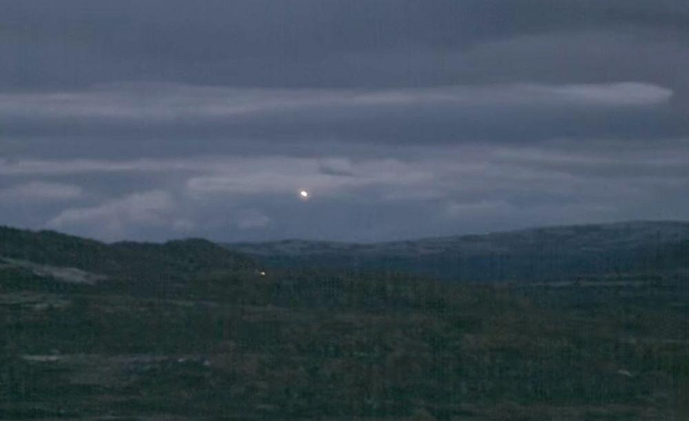Hesdālenes gaismas 2015. gada februārī. Redzamas divas kustīgas gaismas - viena ir debesīs (tas nav, piemēram, Mēness) un otrai fonā ir mežs.